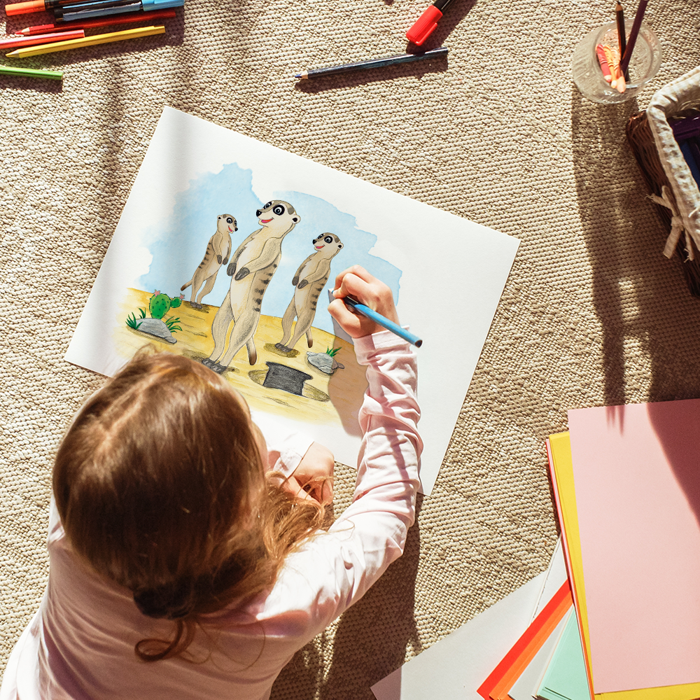 Kind liegt auf dem Boden und zeichnet Erdmännchen