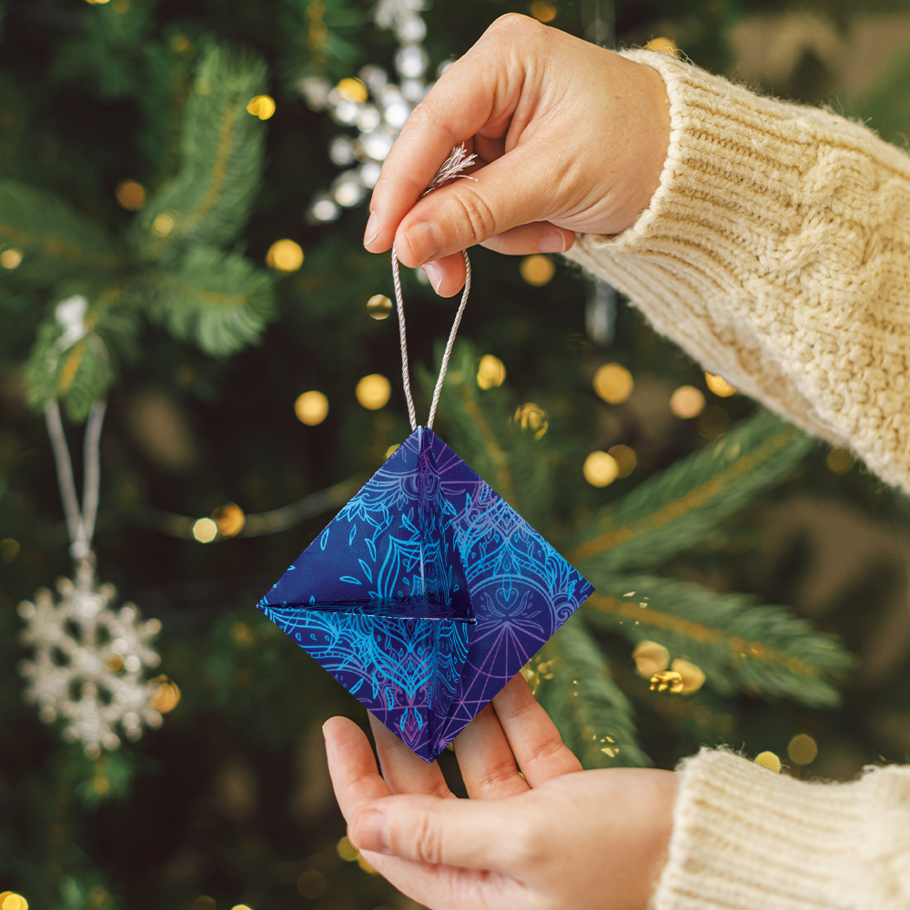 Origami-Anhänger für den Weihnachtsbaum in der Hand einer Frau